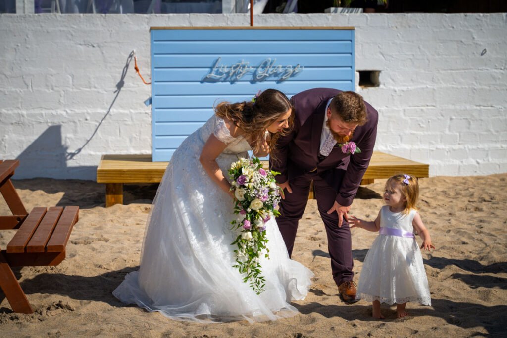 bride and groom with daughter on the beach