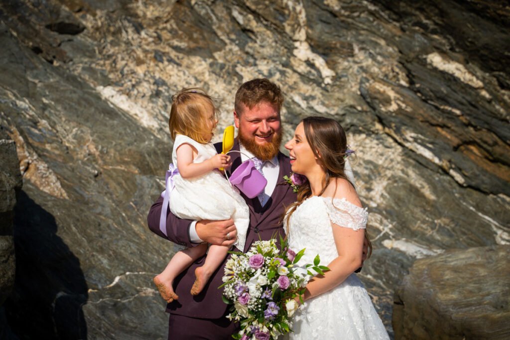 bride and groom and daughter on the beach