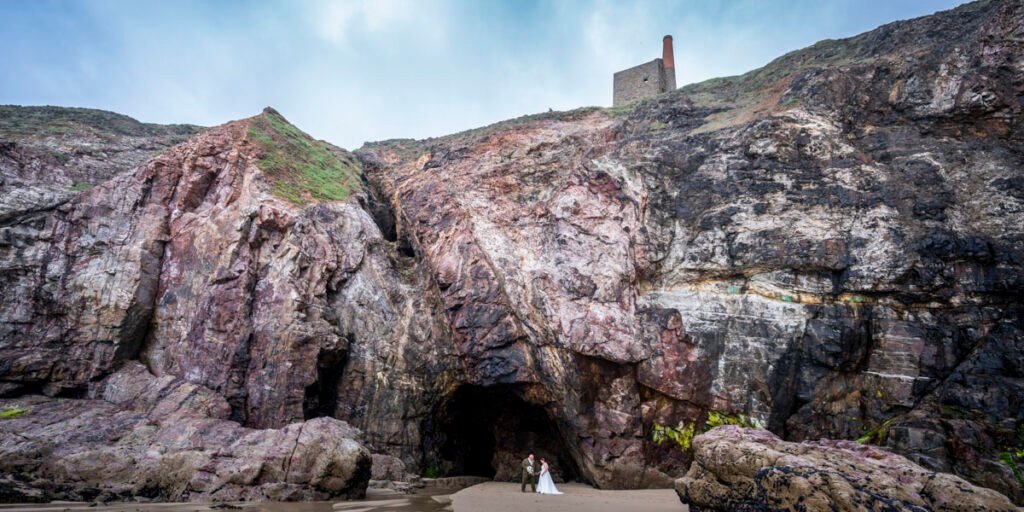 Bride and Groom in front of a cave on Chapel Porth beach cornwall