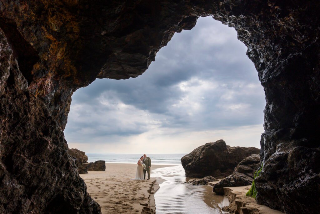 Bride and Groom in front of a cave on Chapel Porth beach cornwall