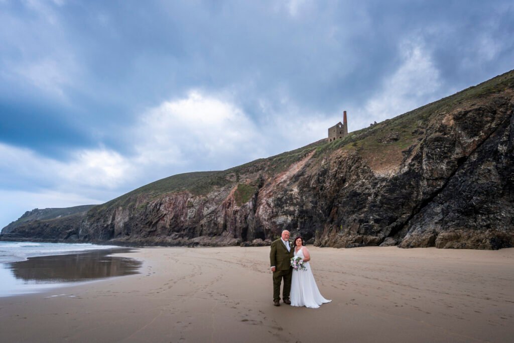 Bride and Groom in front of a cave on Chapel Porth beach cornwall