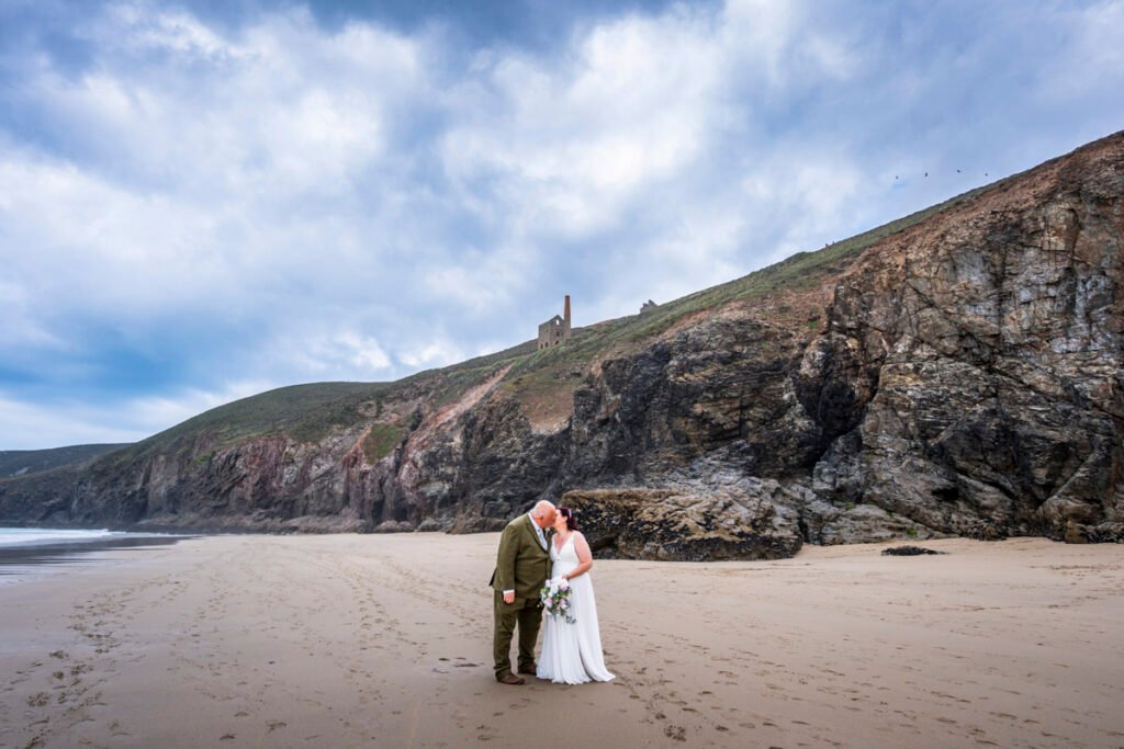 Bride and Groom in front of a cave on Chapel Porth beach cornwall