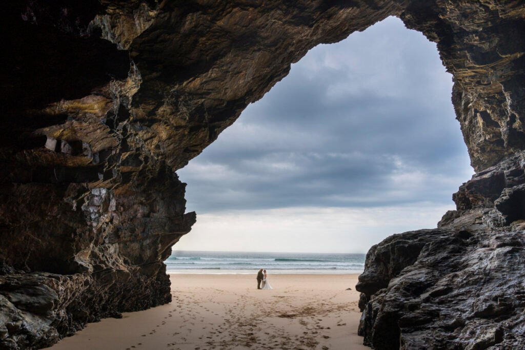 Bride and Groom in front of a cave on Chapel Porth beach cornwall