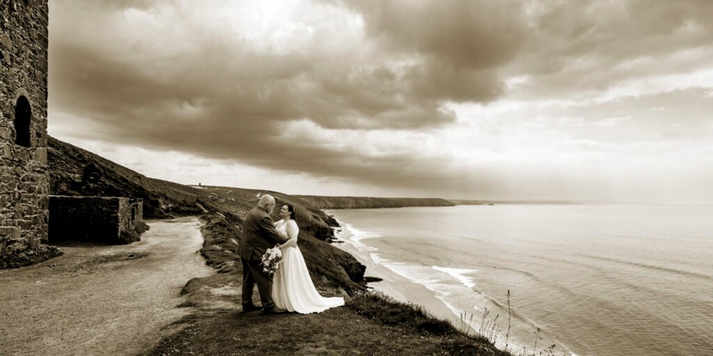 Bride and Groom on the coastpath by Wheal Coates mine engine house sepia