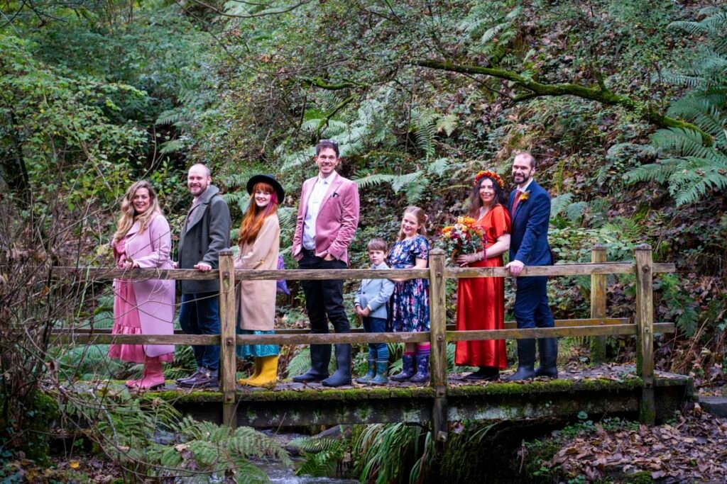 Wedding guests, Bride and Groom on a bridge over a stream