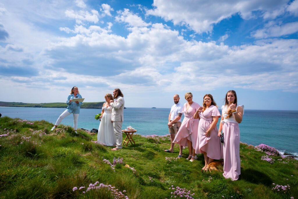 bride and groom and bridal party at the wedding ceremony on the cliff top overlooking the beach