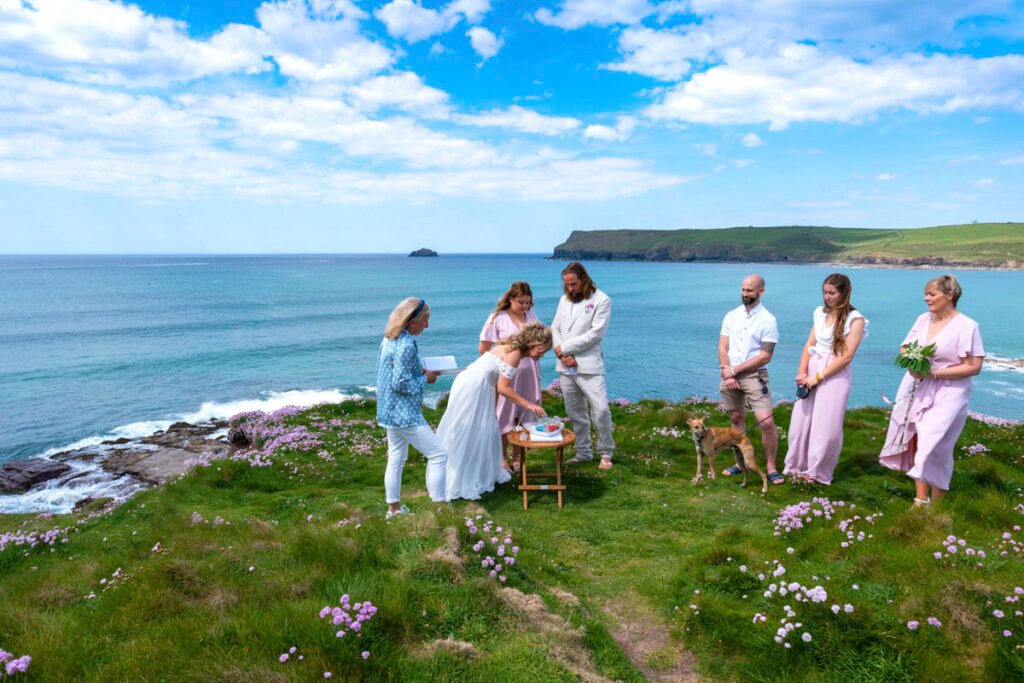 bride signing the register at the wedding ceremony on the cliff top overlooking the beach