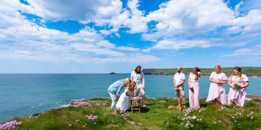 bride signing the register at the wedding ceremony on the cliff top overlooking the beach