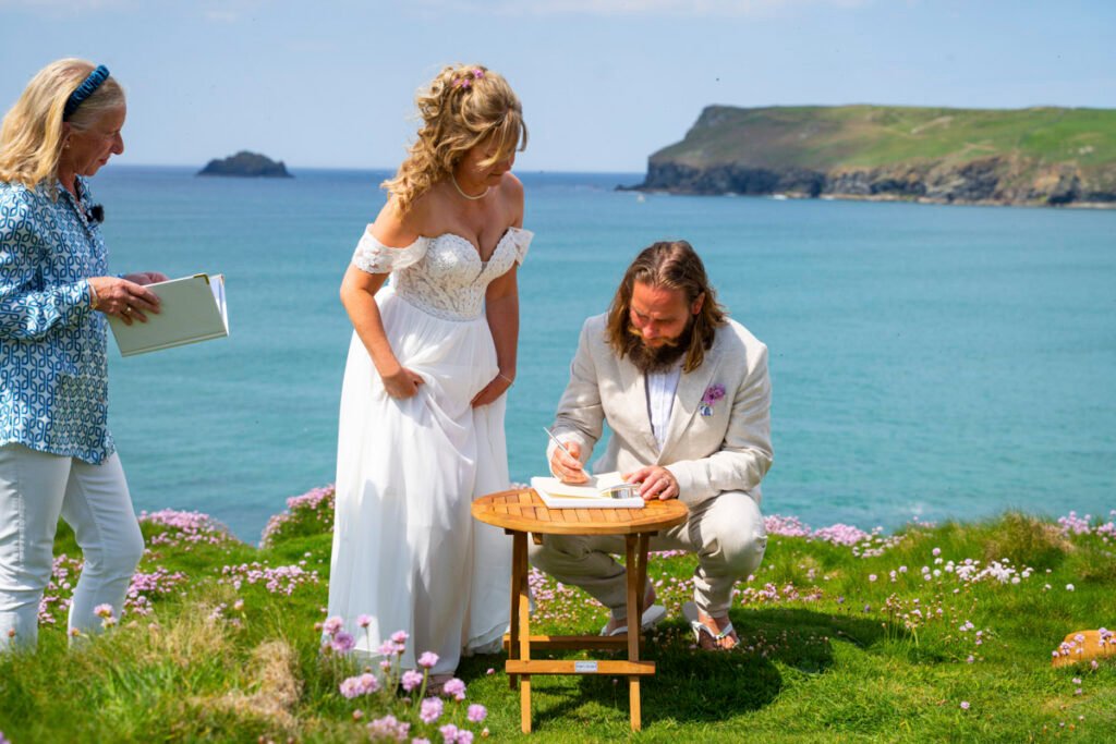groom signing the register at the wedding ceremony on the cliff top overlooking the beach
