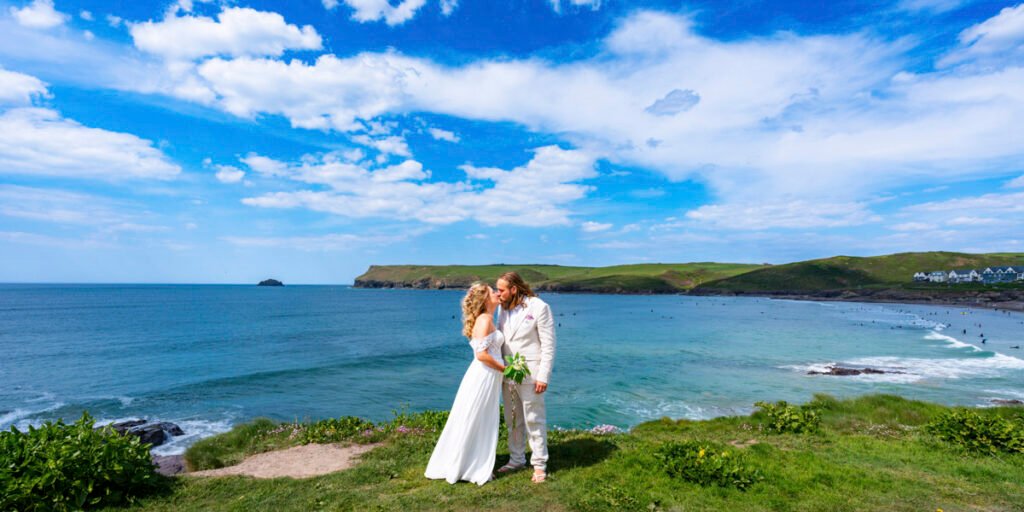 Bride and Groom kissing on the cliff top overlooking the beach