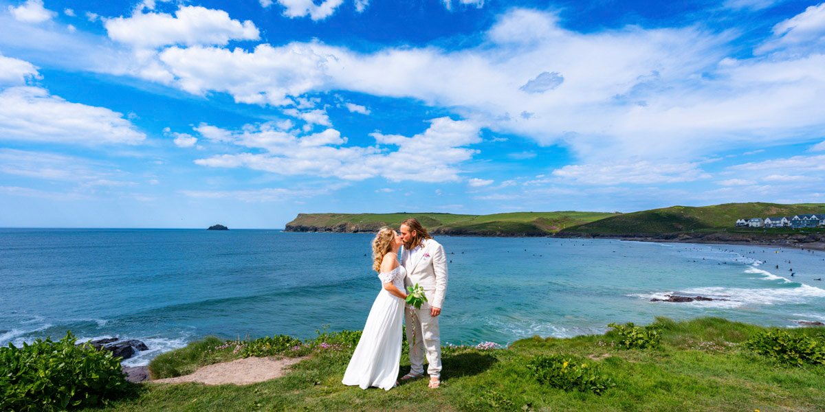 Bride and Groom kissing on the cliff top overlooking the beach