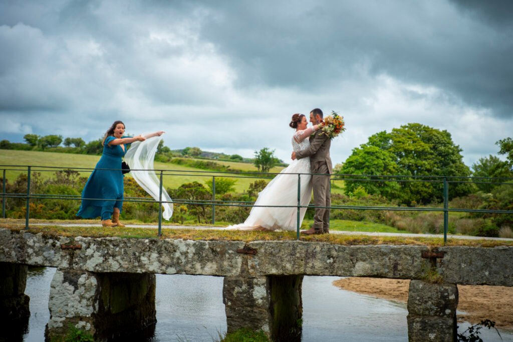 Bride and Groom on a bridge on the Moors with a bridesmaid veil in the wind