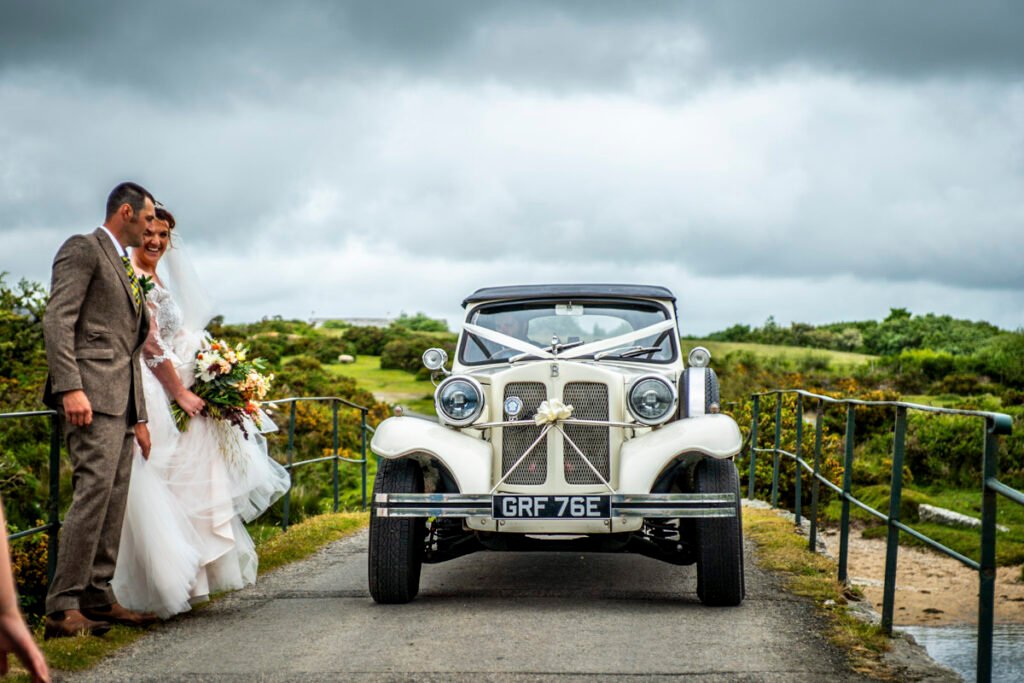 Bride and Groom on the Moors with the wedding car