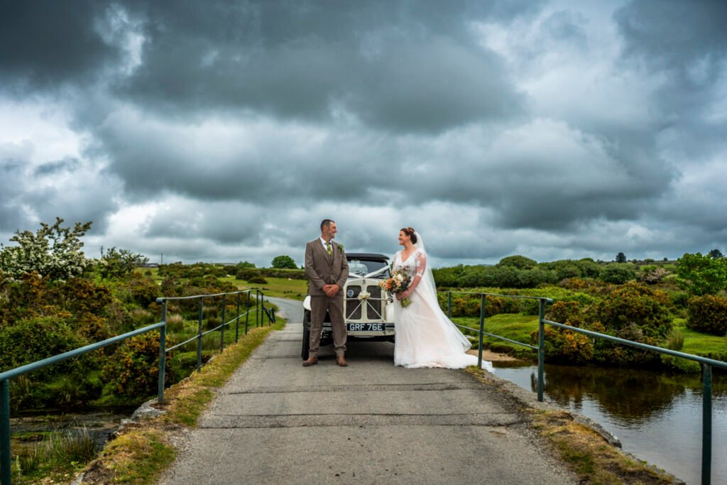 Bride and Groom on the Moors with the wedding car