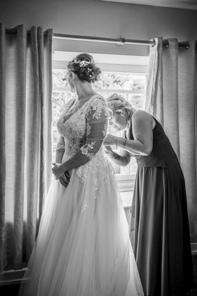 Bride and Bridesmaid fastening the dress B&W