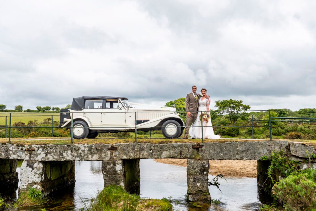 Bride and Groom on a bridge with the wedding car